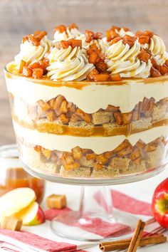 an apple dessert with whipped cream and caramel toppings in a glass trifle dish