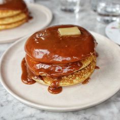 pancakes covered in syrup and butter on a white plate