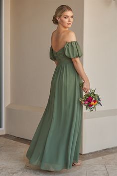 a woman in a long green dress holding a bouquet and looking off to the side