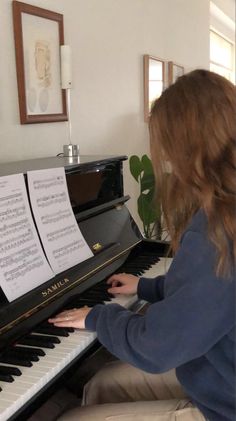 a woman sitting at a piano with sheet music on it