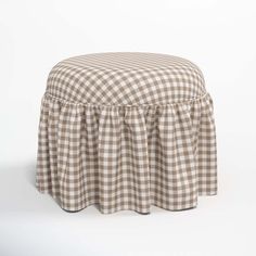 a brown and white checkered ottoman with a ruffled skirt on the bottom, sitting in front of a white background