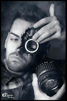 a man holding a camera up to his face with the lens in front of him