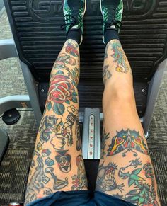 a person with tattoos on their legs is sitting on a treadmill and holding a remote control