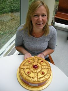 a woman sitting at a table with a cake in front of her and smiling for the camera