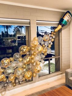 the balloon arch is decorated with gold, silver and white balloons in front of a living room window