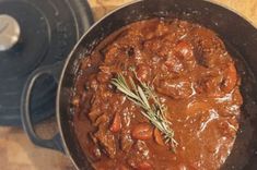 a pot filled with stew sitting on top of a wooden table