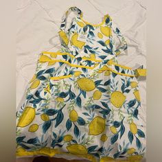 a yellow and white dress with lemons on it sitting on top of a bed