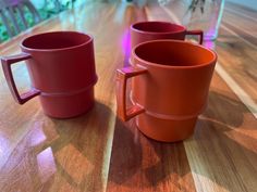 two red mugs sitting on top of a wooden table