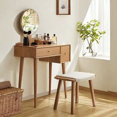 a wooden desk with a mirror and stool in a white room next to a potted plant