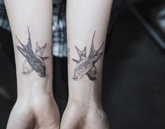 two matching tattoos on both arms with birds in the middle one is black and white