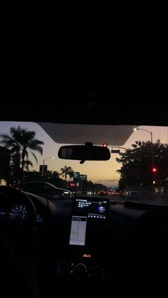 the dashboard of a car at night with palm trees in the background