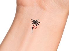 a small palm tree with a heart tattoo on the left side of the wrist is shown