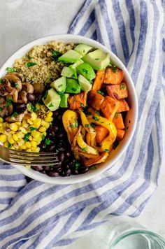 a bowl filled with vegetables and rice on top of a blue and white striped towel