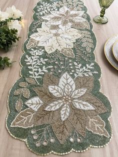 a table runner with flowers and leaves on it, along with plates and vases