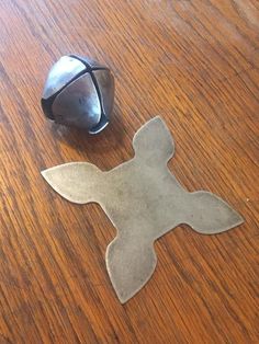 a metal object sitting on top of a wooden table next to a silver cup and saucer