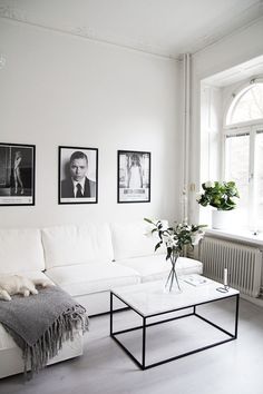 a living room with white furniture and pictures on the wall above it's coffee table