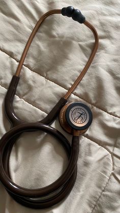 a brown stethoscope laying on top of a white bed sheet with a black cord