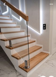 the stairs are made of wood and have glass railings on each handrail, along with an illuminated light above them