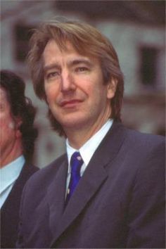 a man in a suit and tie standing next to another man wearing a blue tie