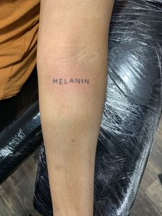 a woman's leg with the word melanin tattooed on it