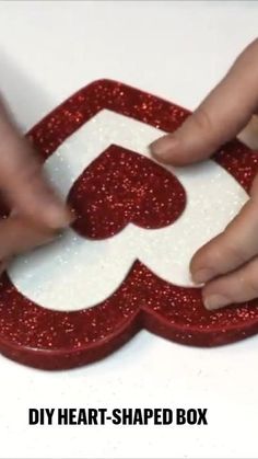 two hands holding a red and white heart shaped box