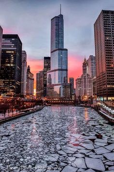 the city skyline is lit up at night with ice floes on the water and large skyscrapers in the background