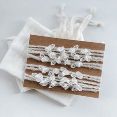 two pieces of white lace with flowers on them sitting on top of a piece of brown paper