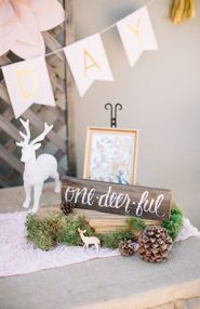 a wooden sign sitting on top of a table next to pine cones and other decorations