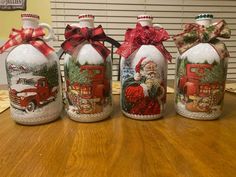 three decorated glass bottles sitting on top of a wooden table covered in christmas decorations and bows