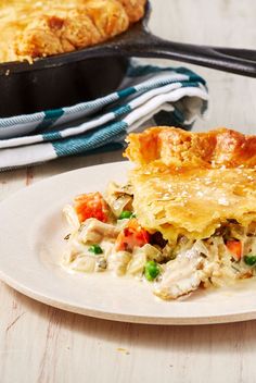 a white plate topped with chicken pot pie next to a pan filled with casserole