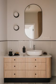 a bathroom with a large mirror above the sink and wooden cabinetry on the wall