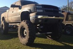 a large gray truck parked on top of a lush green field