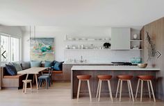 an open kitchen and living room area with stools on the floor, counter tops, and cabinets