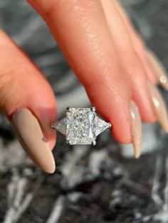 a woman's hand holding a diamond ring