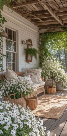 a porch covered in lots of white flowers and greenery next to a wooden bench