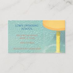 a business card with an image of a yellow umbrella in the water on a white marble surface