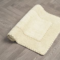 a white rug is laying on the floor next to a gray wooden floor and grey wood floors