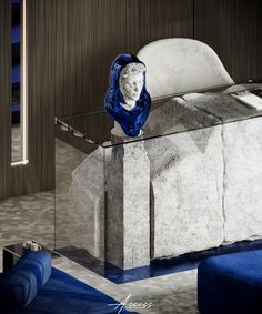 a marble sculpture sitting on top of a table next to a blue chair and ottoman