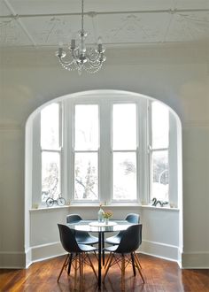 a dining room table with four chairs and a chandelier hanging from the ceiling