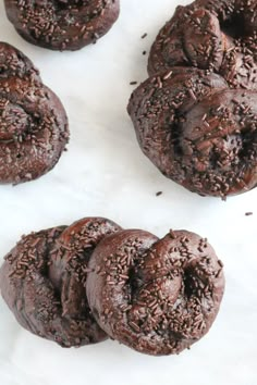 chocolate cookies with sprinkles are on a white paper lined baking sheet, ready to be eaten