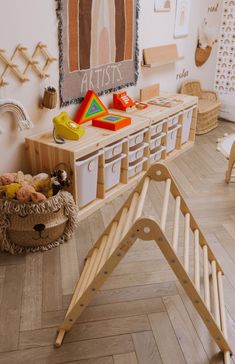 a child's play room with wooden furniture and artwork on the wall above it