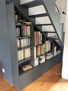 a bookshelf with many books on it and stairs above the bookcases