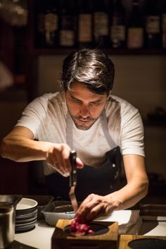 a man in an apron chopping meat on a cutting board