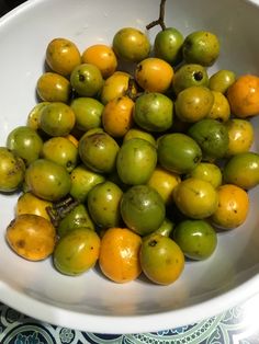 a white bowl filled with lots of green and yellow fruit on top of a table