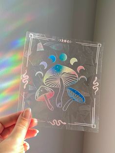 a person holding up a clear sticker with colorful designs on it