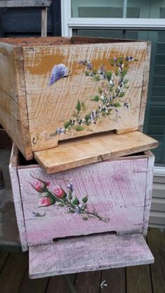 three wooden boxes are stacked on top of each other, with flowers painted on them