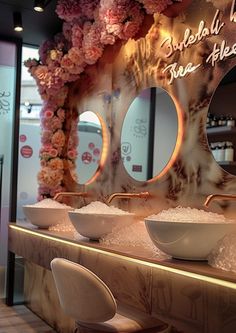 two sinks and mirrors in a room with flowers on the wall