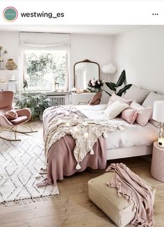 a bedroom with white walls and wooden floors, pink bedding, rugs on the floor