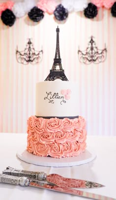 a pink and white cake with the eiffel tower on top is next to scissors