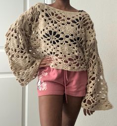 a woman wearing shorts and a crocheted sweater